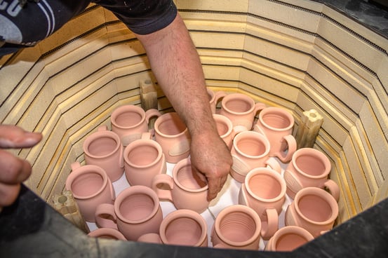 Wade Pratt putting ceramic mugs into a kiln